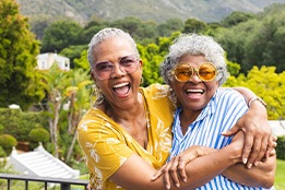 Two women laughing and embracing outside