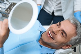 a patient checking his dental implants with a mirror
